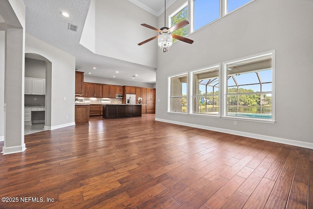 1211 Spring Branch Rd, Saint Johns, FL 32259 - unfurnished living room featuring baseboards, ceiling fan, dark wood finished floors, arched walkways, and a towering ceiling