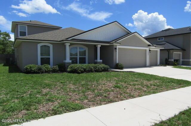 2985 Vianey Pl, Green Cove Springs, FL 32043 - craftsman house featuring a garage, concrete driveway, a front yard, and stucco siding