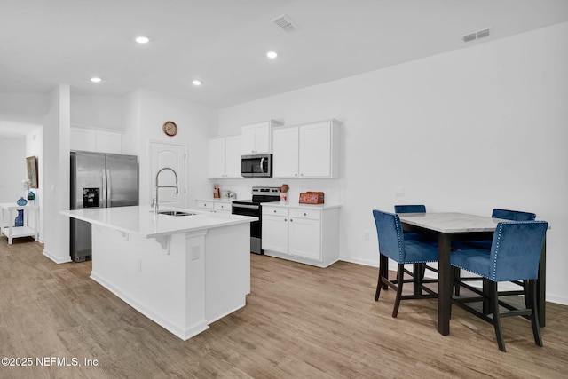 3075 Rustic Deer Way, Green Cove Springs, FL 32043 - kitchen featuring appliances with stainless steel finishes, a center island with sink, light wood finished floors, a kitchen breakfast bar, and light countertops