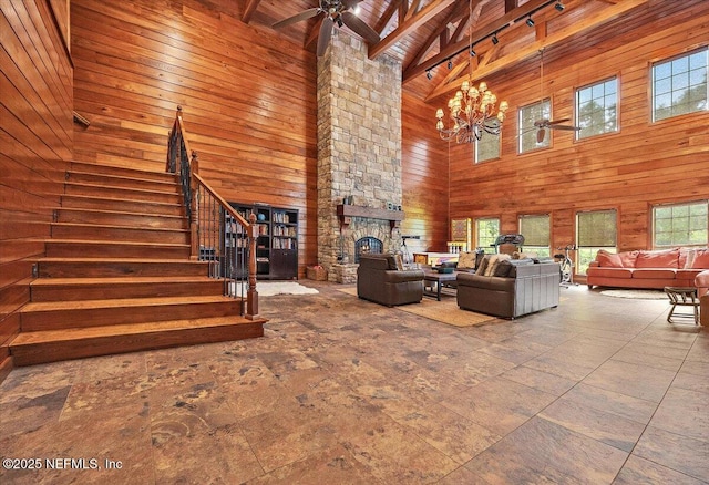 3355 Bishop Estates Rd, Saint Johns, FL 32259 - living room featuring high vaulted ceiling, wood walls, stairway, a ceiling fan, and a stone fireplace