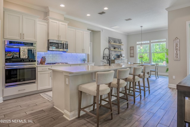 310 Cedarstone Way, Saint Augustine, FL 32092 - kitchen featuring stainless steel appliances, a sink, light countertops, a kitchen island with sink, and light wood-style flooring