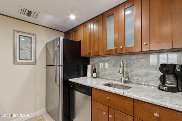 278 Sandcastles Ct, Fernandina Beach, FL 32034 - kitchen with appliances with stainless steel finishes, a sink, brown cabinetry, and light stone counters