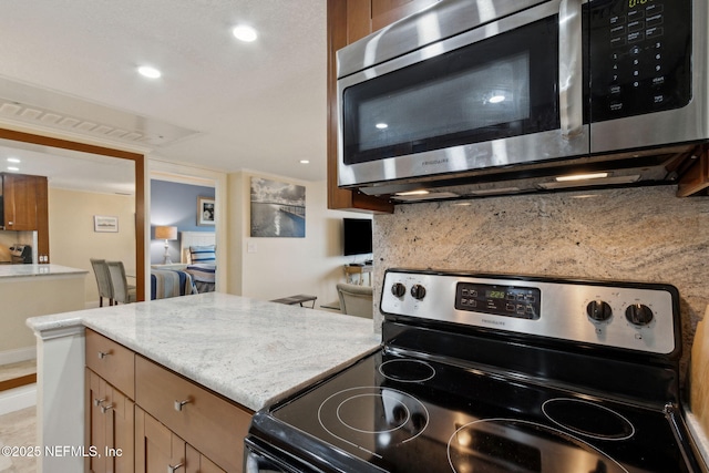278 Sandcastles Ct, Fernandina Beach, FL 32034 - kitchen featuring stainless steel appliances, tasteful backsplash, brown cabinetry, recessed lighting, and light stone countertops