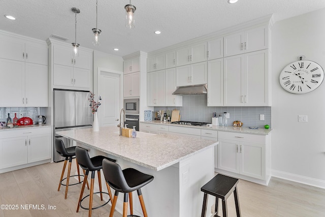 144 Waverly Way, Saint Johns, FL 32259 - kitchen with appliances with stainless steel finishes, under cabinet range hood, a kitchen bar, light wood finished floors, and recessed lighting