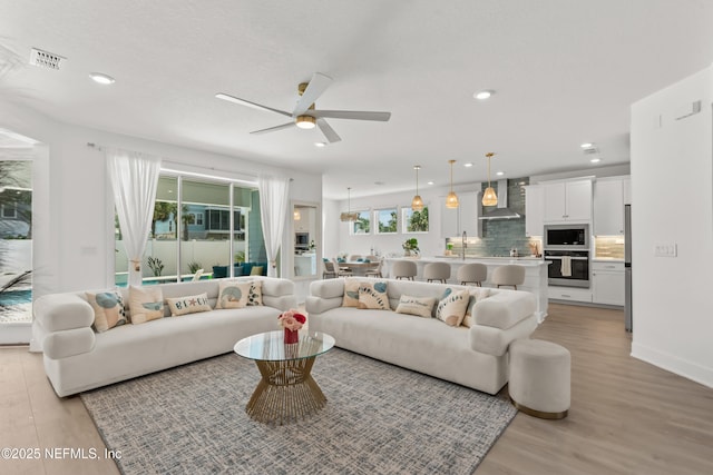 living room with ceiling fan, light wood-style flooring, and recessed lighting