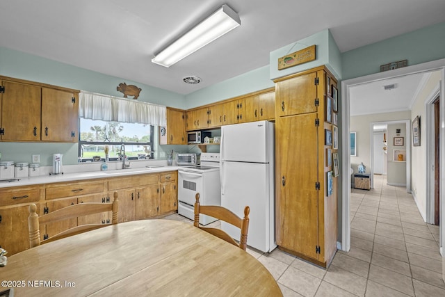 kitchen with white appliances, a sink, light tile patterned floors, and light countertops
