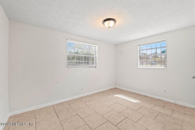 4504 Lincrest Dr S, Jacksonville, FL 32208 - unfurnished room featuring healthy amount of natural light, a textured ceiling, baseboards, and light tile patterned flooring