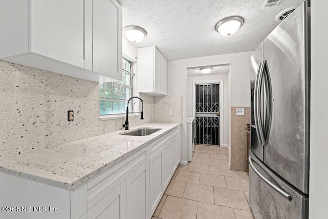 4504 Lincrest Dr S, Jacksonville, FL 32208 - kitchen featuring stainless steel fridge with ice dispenser, a sink, white cabinetry, light stone countertops, and a textured ceiling