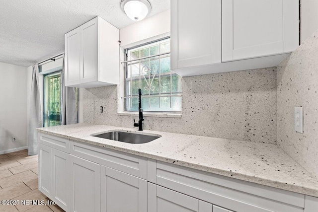 4504 Lincrest Dr S, Jacksonville, FL 32208 - kitchen with a sink, white cabinetry, decorative backsplash, light stone countertops, and a textured ceiling