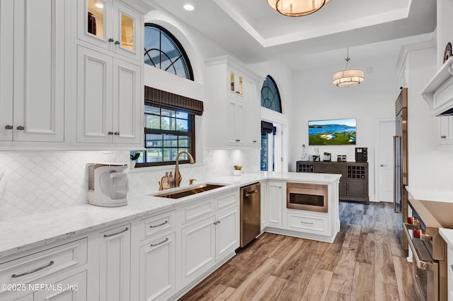 108 Spanish Moss Ln, Ponte Vedra Beach, FL 32082 - kitchen with stainless steel dishwasher, a sink, white cabinetry, light wood-style floors, and a peninsula