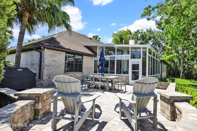 108 Spanish Moss Ln, Ponte Vedra Beach, FL 32082 - rear view of property featuring a patio, brick siding, a sunroom, a shingled roof, and a chimney