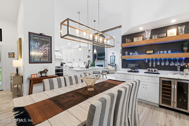 33 Loggerhead Ln, Ponte Vedra Beach, FL 32082 - dining room featuring beverage cooler, a high ceiling, light wood finished floors, bar area, and recessed lighting