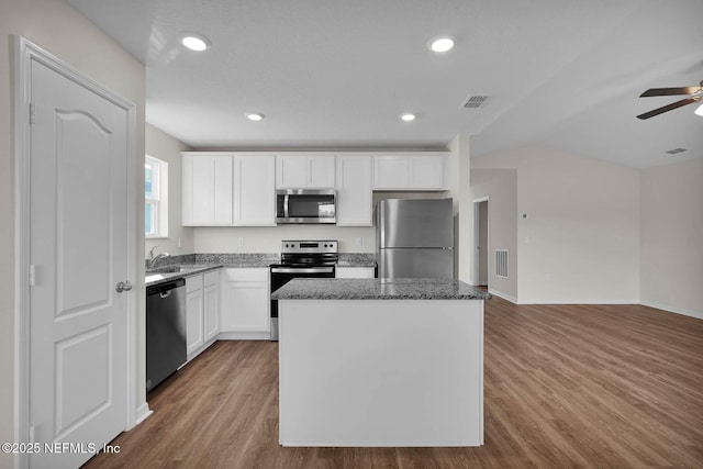 37135 Whippoorwill Ct, Hilliard, FL 32046 - kitchen with stainless steel appliances, a center island, ceiling fan, dark stone countertops, and wood finished floors