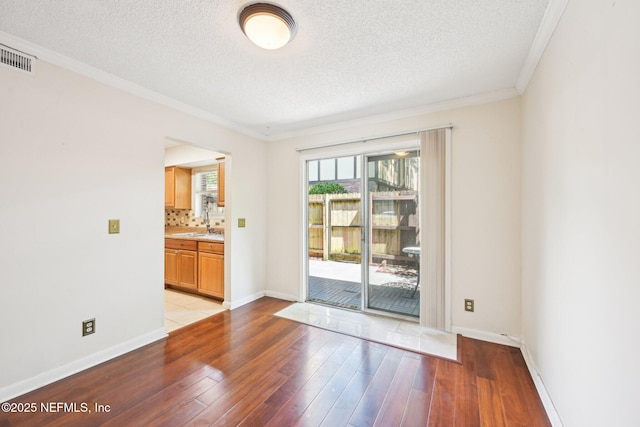 4813 Cherwell Ln Unit B-4-C, Jacksonville, FL 32217 - unfurnished room with a sink, light wood-style flooring, a textured ceiling, crown molding, and baseboards