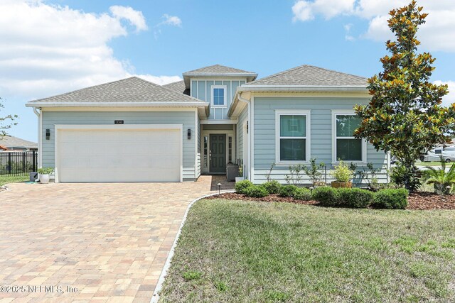 view of front of home featuring an attached garage, decorative driveway, and a shingled roof