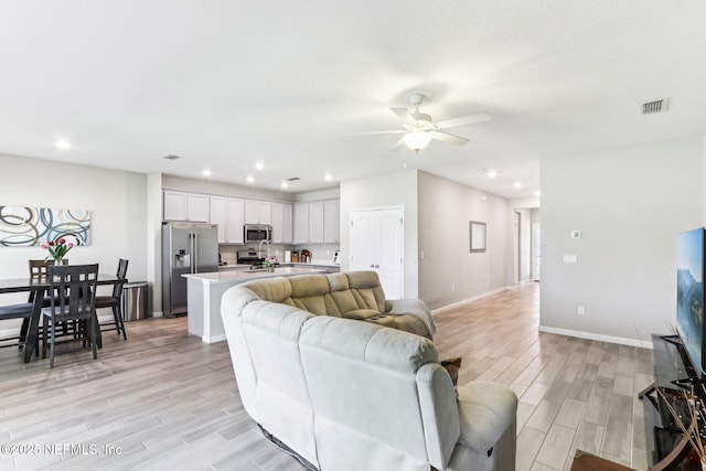 living area featuring light wood-style flooring, a ceiling fan, recessed lighting, and baseboards