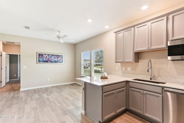 kitchen with stainless steel appliances, gray cabinets, a sink, ceiling fan, and a peninsula
