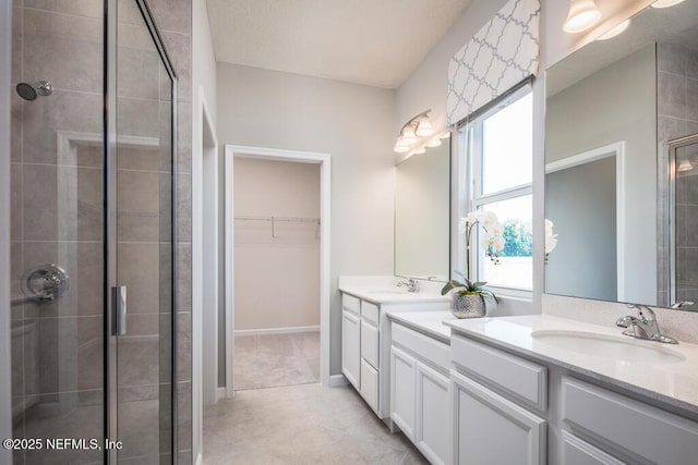 bathroom featuring a stall shower, a walk in closet, double vanity, and tile patterned flooring