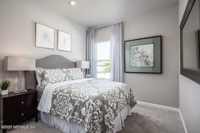 bedroom with carpet floors, baseboards, and a textured ceiling