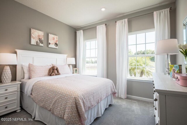 bedroom with multiple windows, light carpet, and baseboards
