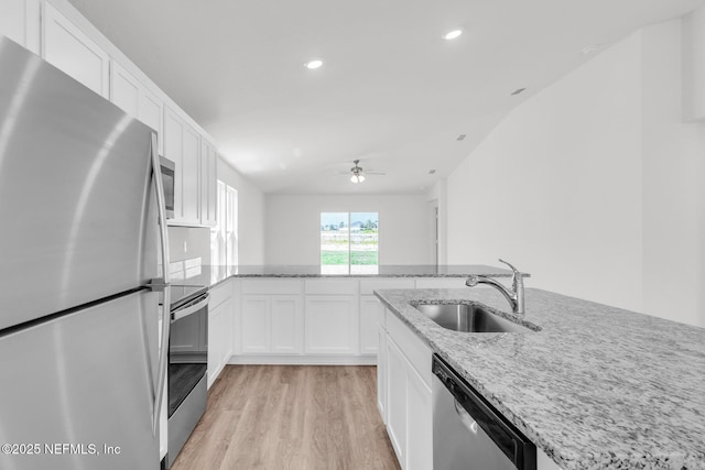 37143 Whippoorwill Ct, Hilliard, FL 32046 - kitchen featuring stainless steel appliances, a sink, light wood-style flooring, white cabinets, and light stone countertops