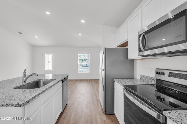 37143 Whippoorwill Ct, Hilliard, FL 32046 - kitchen with appliances with stainless steel finishes, a sink, white cabinetry, light wood-style floors, and light stone counters