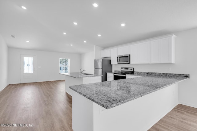37143 Whippoorwill Ct, Hilliard, FL 32046 - kitchen with appliances with stainless steel finishes, a sink, a center island with sink, light wood finished floors, and recessed lighting