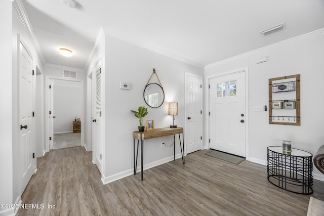 foyer featuring wood finished floors, crown molding, and baseboards