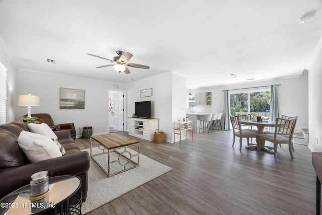 living room with wood finished floors, ceiling fan, baseboards, and ornamental molding