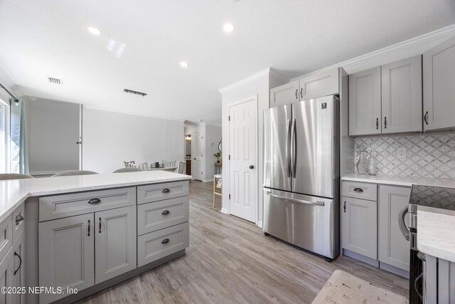 kitchen with freestanding refrigerator, gray cabinetry, decorative backsplash, light wood-style flooring, and recessed lighting