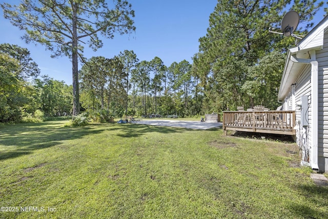 view of grassy yard featuring a deck and view of scattered trees