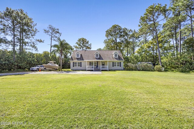cape cod home with covered porch, a front lawn, and view of scattered trees