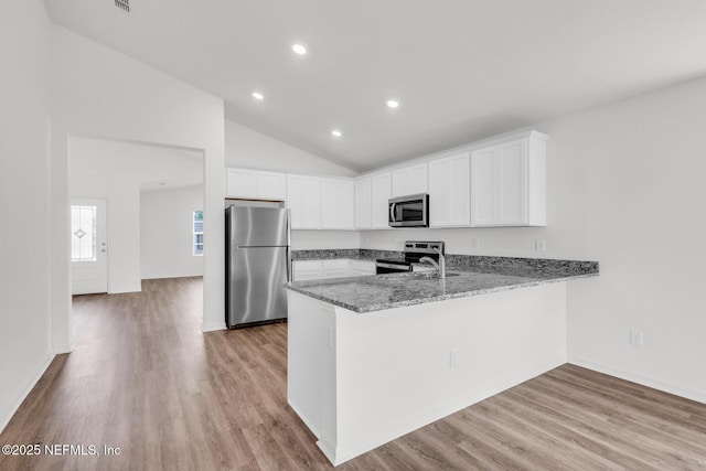 37127 Whippoorwill Ct, Hilliard, FL 32046 - kitchen with stainless steel appliances, a peninsula, light stone counters, light wood-style floors, and white cabinets