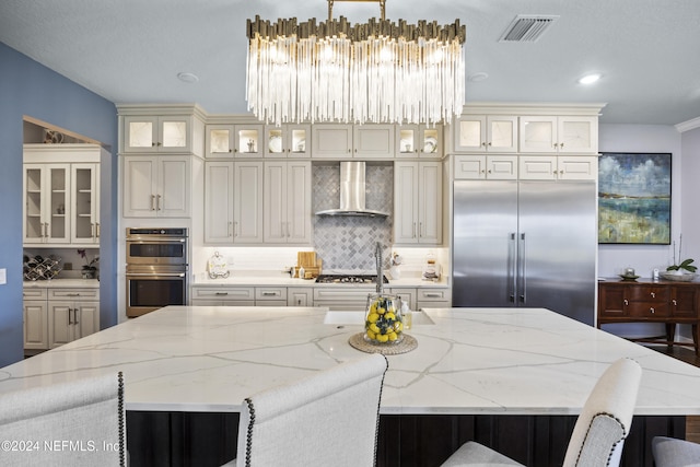228 Rum Runner Way, Saint Johns, FL 32259 - kitchen featuring wall chimney exhaust hood, stainless steel appliances, a large island with sink, a kitchen bar, and tasteful backsplash
