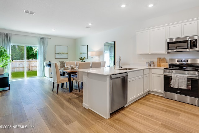 573 Holly Lakes Dr, Orange Park, FL 32073 - kitchen featuring stainless steel appliances, light wood-style floors, white cabinets, recessed lighting, and a sink