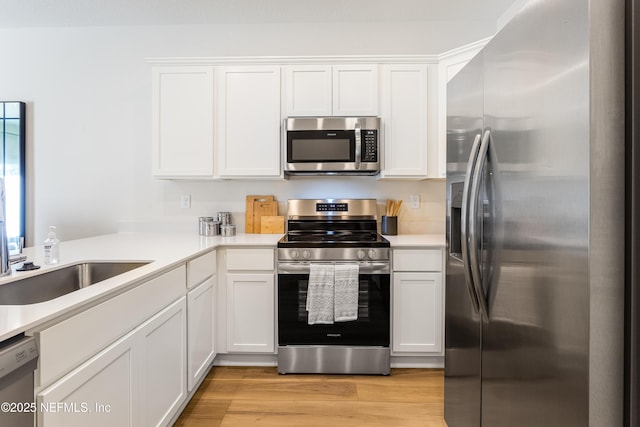 573 Holly Lakes Dr, Orange Park, FL 32073 - kitchen with stainless steel appliances, white cabinetry, light countertops, and light wood-type flooring