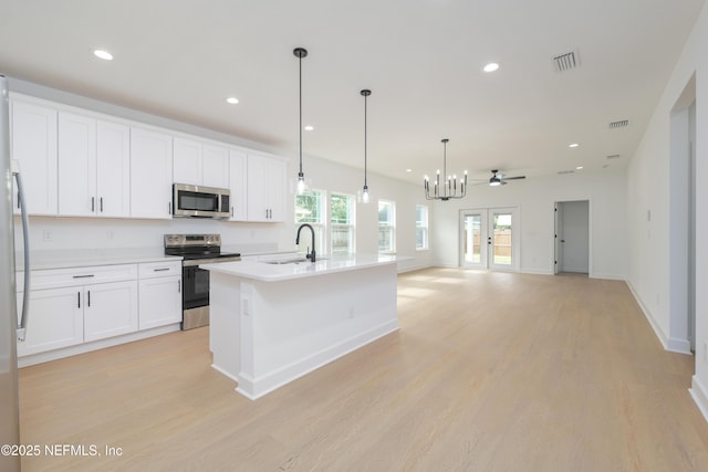 965 Florida St, Fleming Island, FL 32003 - kitchen with stainless steel appliances, a sink, light wood-type flooring, white cabinetry, and a chandelier