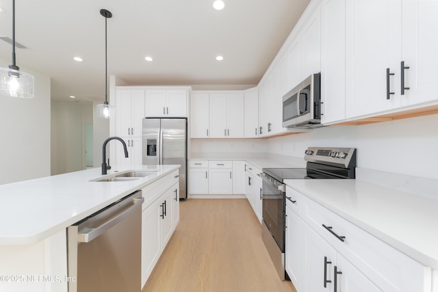 965 Florida St, Fleming Island, FL 32003 - kitchen with stainless steel appliances, a sink, light wood-style flooring, decorative light fixtures, and light countertops