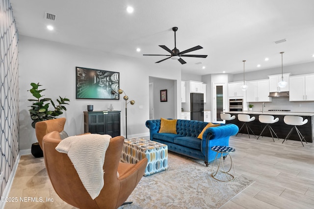living area featuring recessed lighting, a ceiling fan, and baseboards