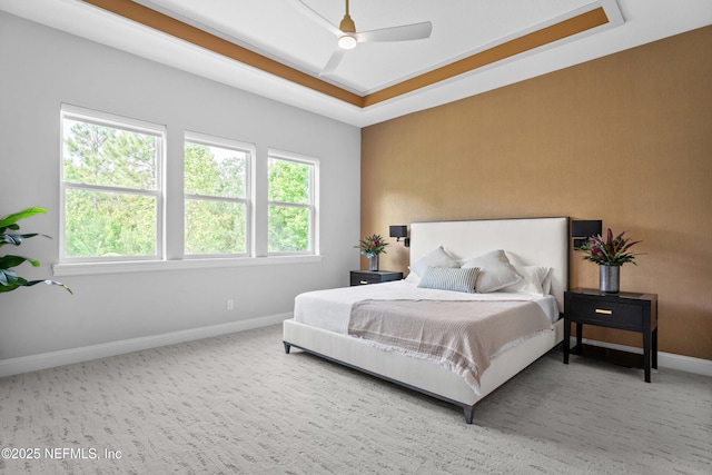 bedroom with baseboards, a raised ceiling, carpet floors, and a ceiling fan