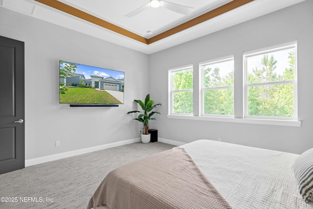 carpeted bedroom featuring a ceiling fan, baseboards, and a raised ceiling