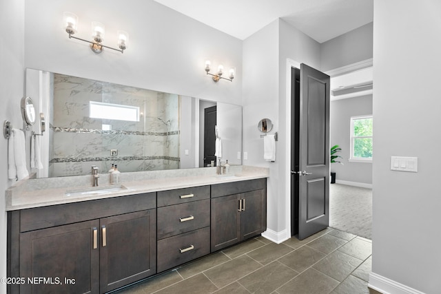 bathroom with a marble finish shower, double vanity, and baseboards