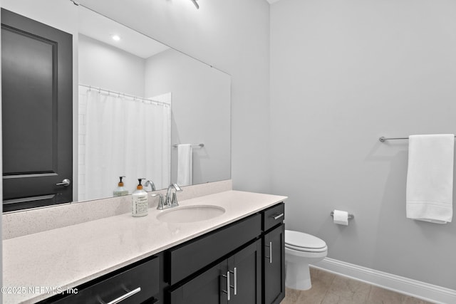 full bathroom featuring toilet, baseboards, and vanity