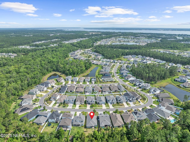 view of property location with a heavily wooded area, nearby suburban area, and a nearby body of water