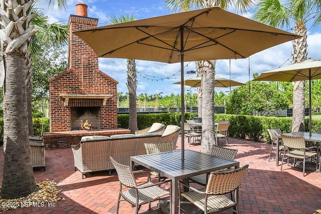 view of patio featuring outdoor dining area and an outdoor brick fireplace