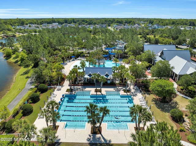 drone / aerial view of a pool area and a tree filled landscape