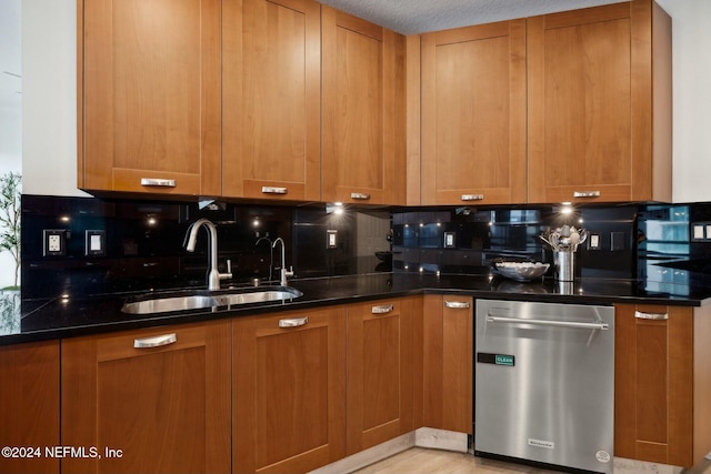 kitchen featuring dishwasher, a sink, backsplash, and brown cabinets