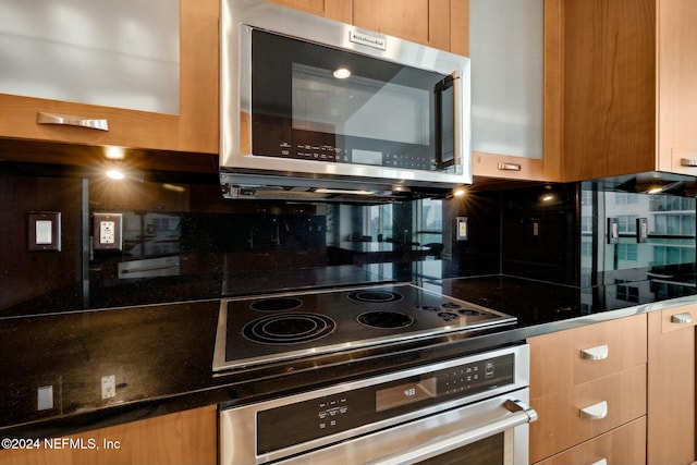 kitchen with stainless steel appliances, backsplash, and dark countertops