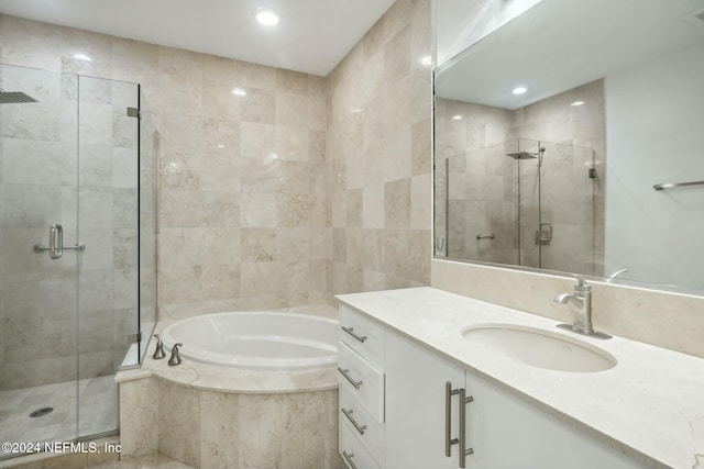 bathroom with a shower stall, a bath, vanity, and recessed lighting