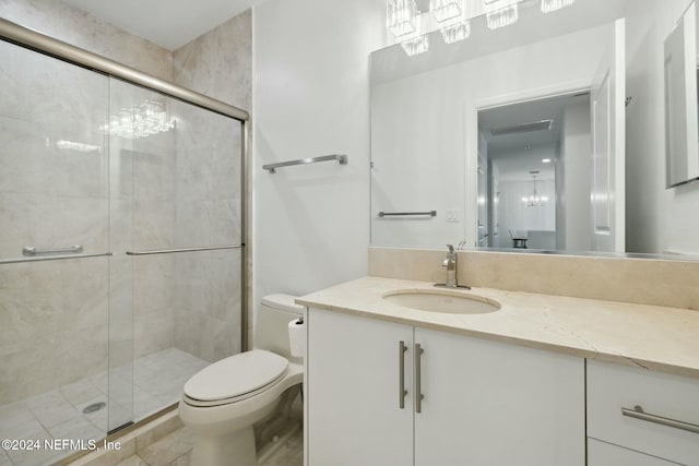 bathroom featuring toilet, a stall shower, vanity, and a chandelier